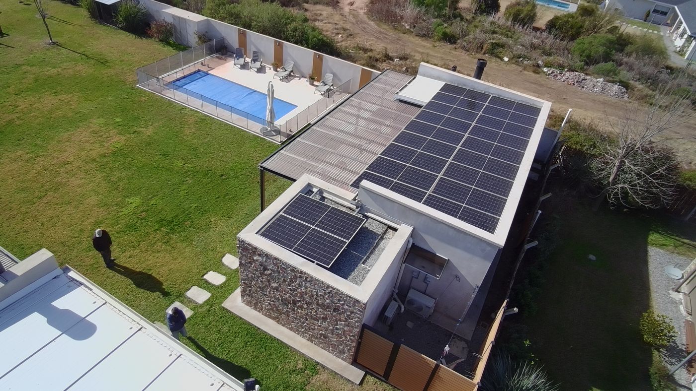 Vista aérea de una casa con piscina, con paneles solares sobre el techo y sobre la barbacoa