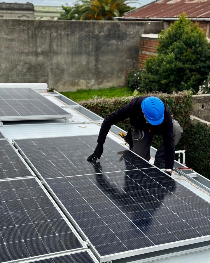Instalador colocando paneles solares sobre el techo de una piscina climatizada